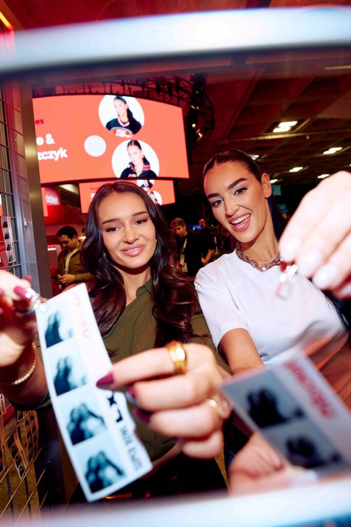 two girls hanging their photo strips at Rocket Mortgage's booth