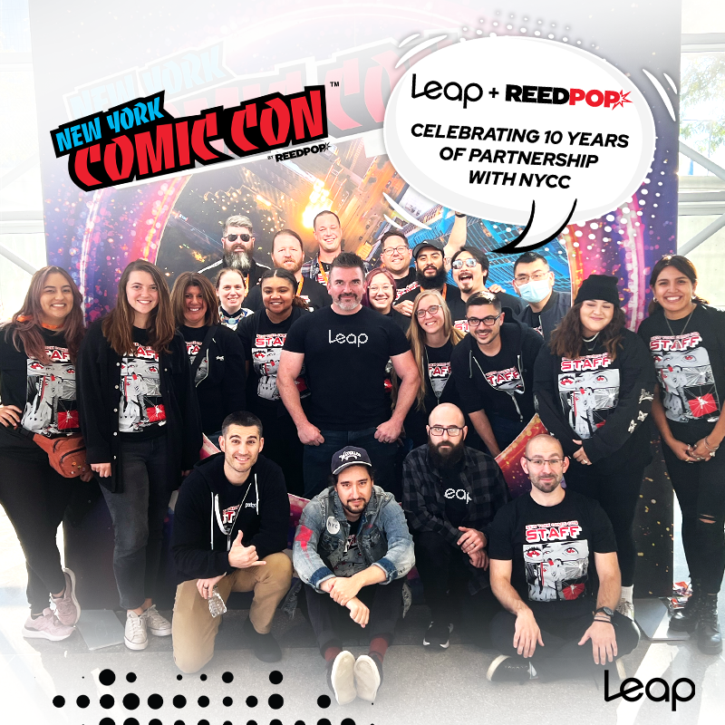 A group of Leap Event Technology employees at New York Comic Con, with a speech bubble above them that reads, "Leap + ReedPop: Celebrating 10 years of partnership with NYCC"