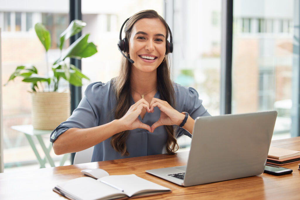 Woman in call center smiling and making a heart with her hands