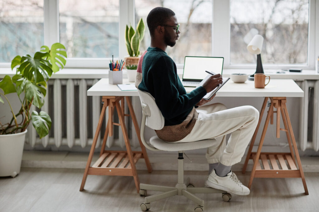 side view portrait of young African-American man wearing glasses while working from home
