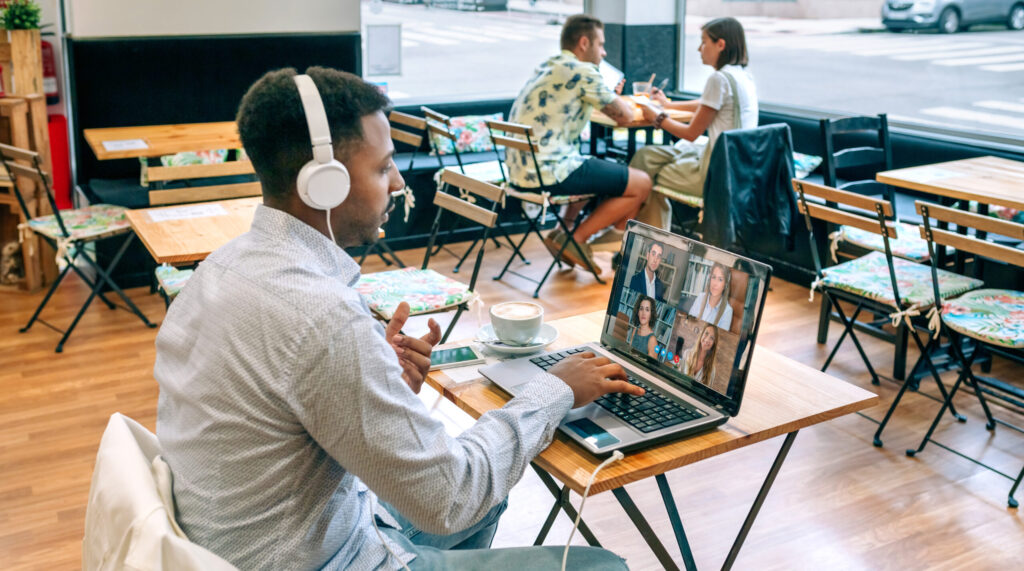 Man in a work meeting by video call from a coffee shop