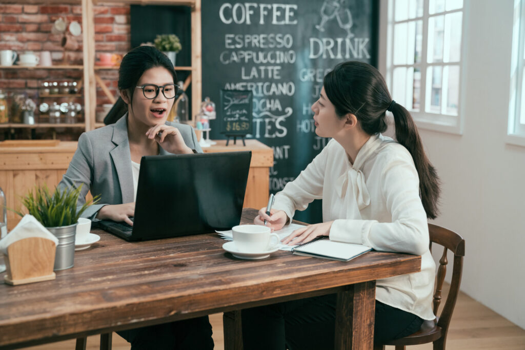 two Asian-American females working together out of a coffee shop