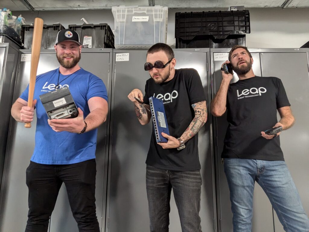 Three warehouse employees in Leap Event Technology shirts, making silly faces