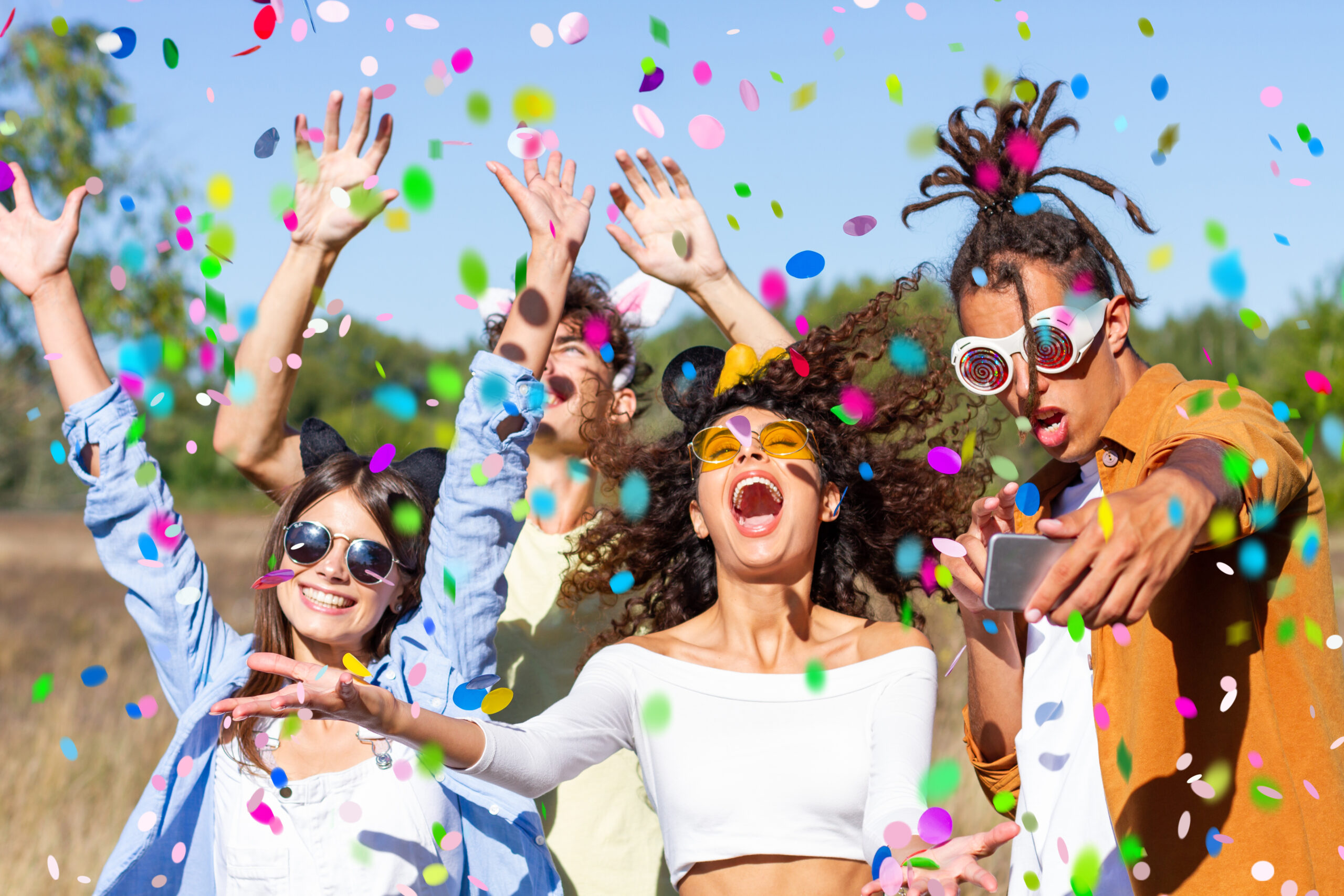 Happy excited friends having fun outdoor celebrating with confetti