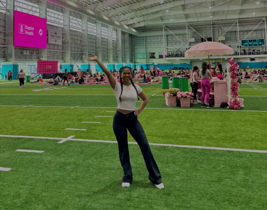 Ariana Singh at a live event on an indoor sports field with lots of pink decorations