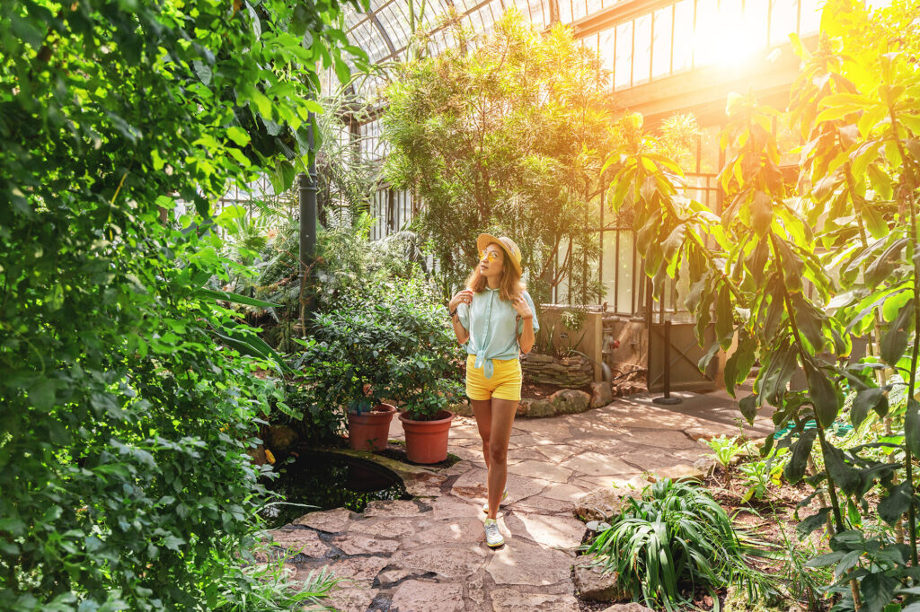 AdobeStock_287252730 Young woman traveler walking in botanical garden