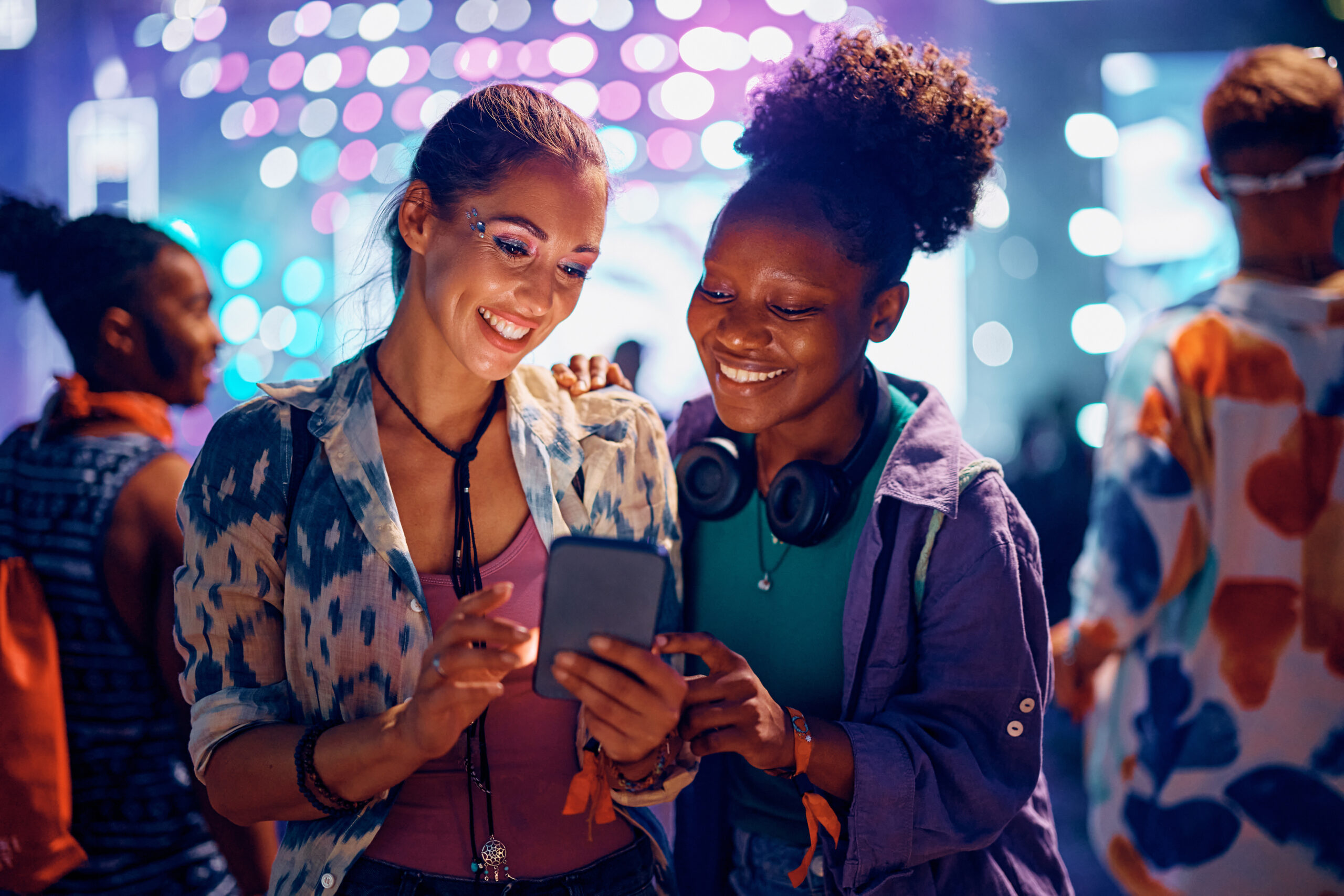 two girls at a festival looking at a phone together