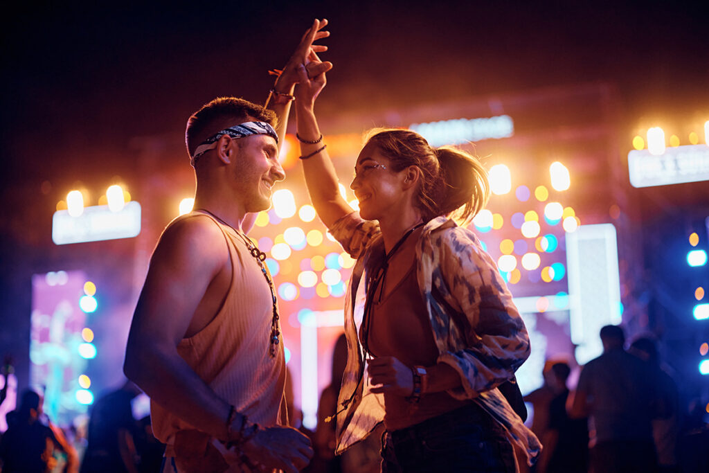 Young happy couple dancing on summer music festival at night. two people dancing at a festival