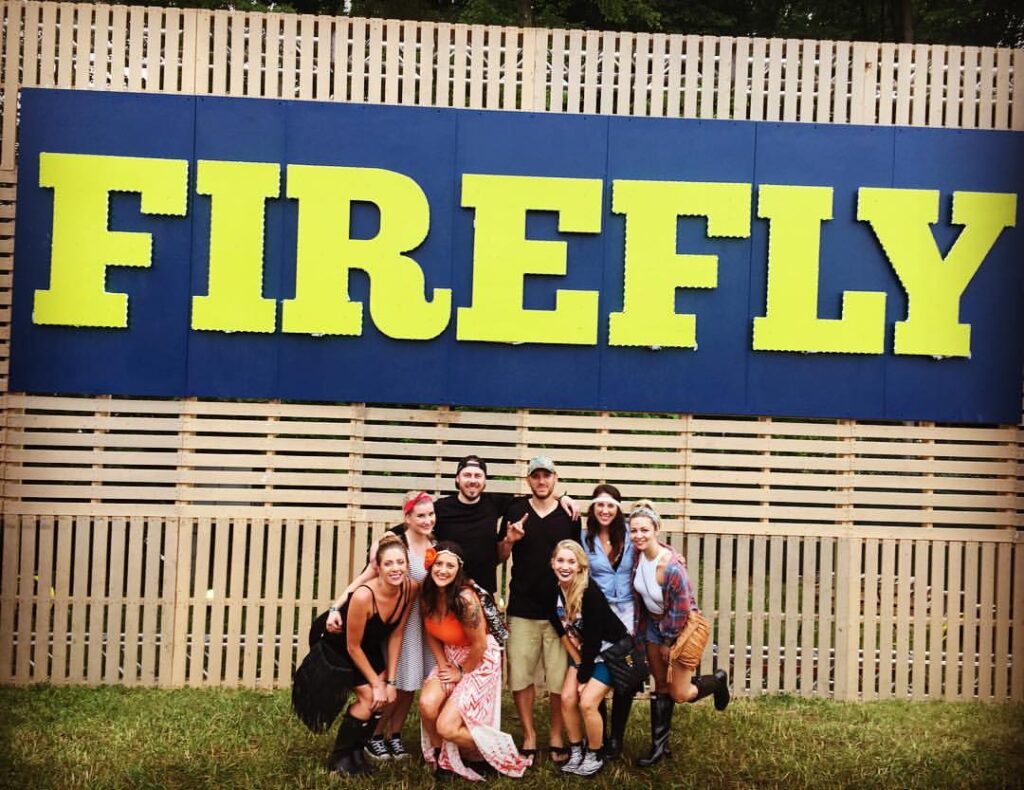 group of friends at Firefly festival in front of photo backdrop