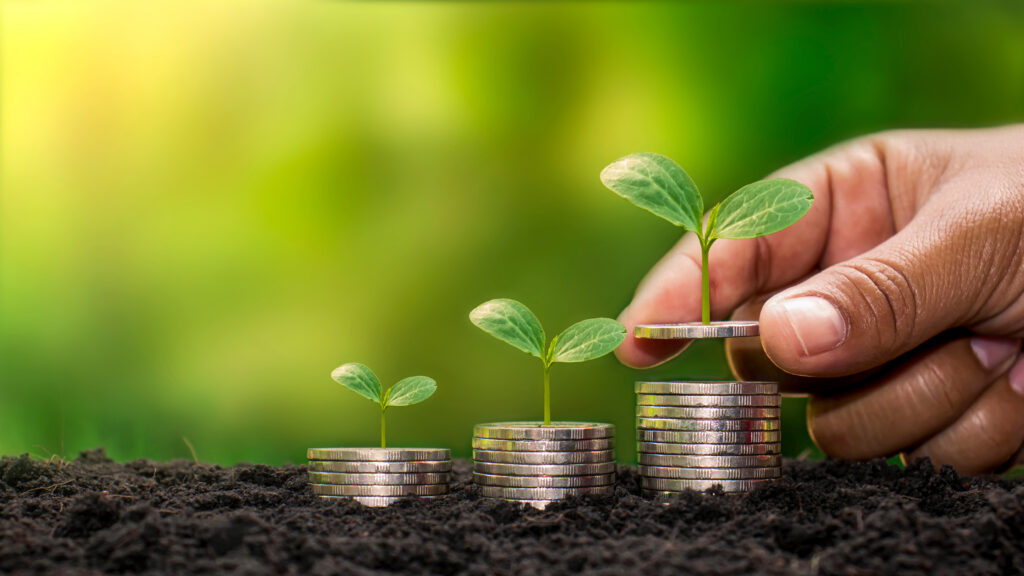 Planting a tree on a pile of money, including the hand of a woman holding a coin to a tree on the coin