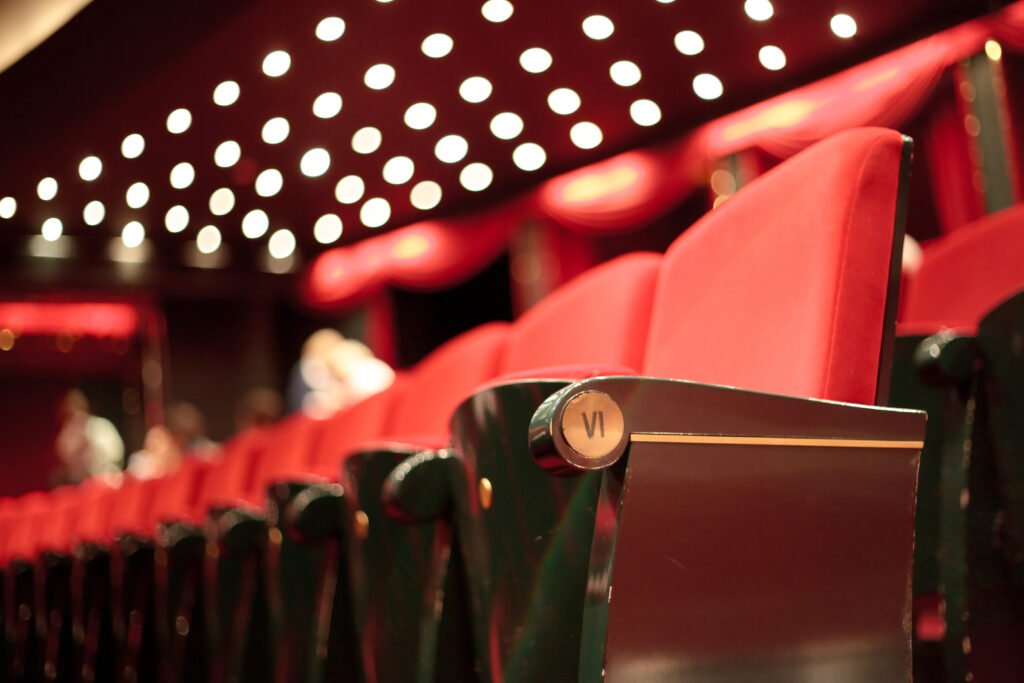 rows of empty theater seats under theater stage lights